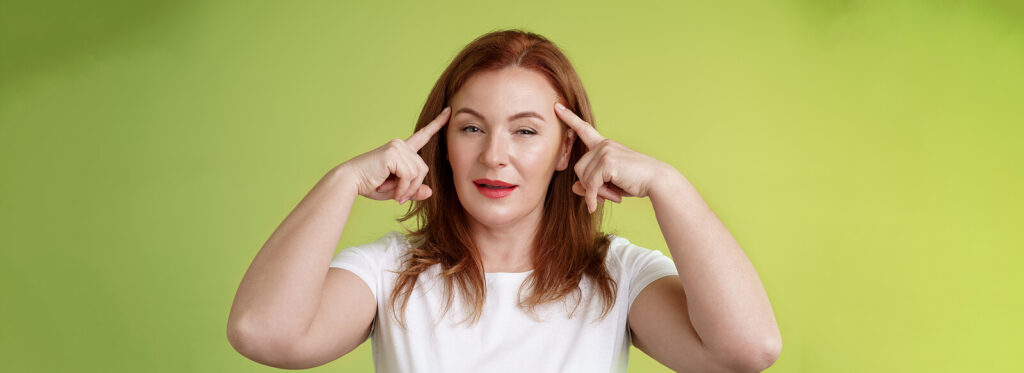 A woman with her fingertips on her forehead pretending to mind read. Couples Therapy in Burbank, CA can help you overcome unrealistic expectations.