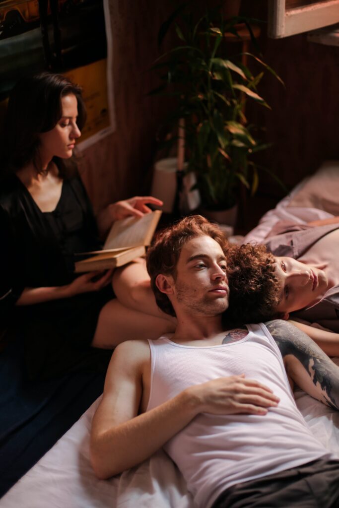 Three people lie together in bed representing an open relationship. Couples Therapy in Burbank, CA can help you navigate the ups and downs of opening your relationship.