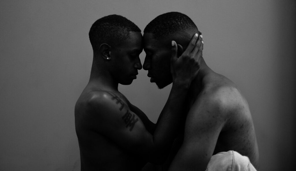 A gay couple sit face to face in an intimate moment that comes from a deeper connection formed in Couples Therapy in Burbank, CA.