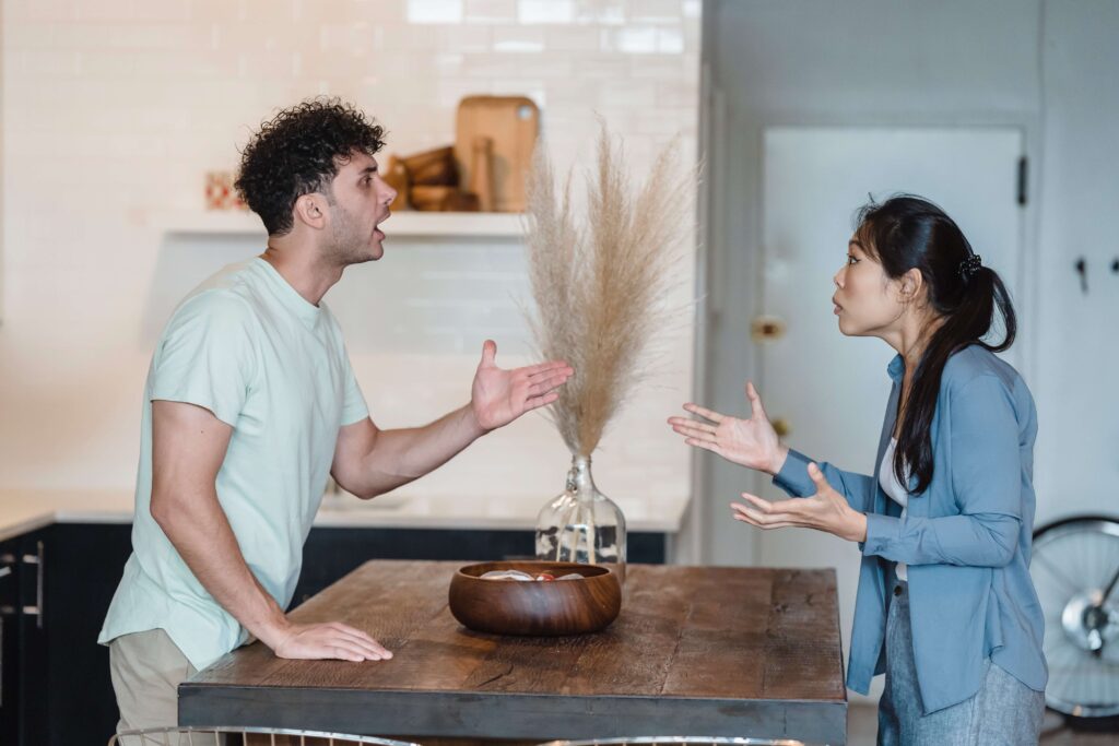 A couple has aggressive body language as they argue in their kitchen representing a couple in need of Couples Therapy in Burbank, CA.